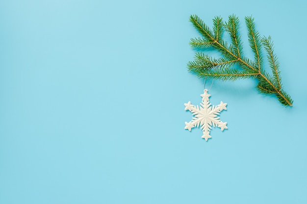 christmas decoration snowflake toy on fir branch on blue background. Concept Merry christmas or Happy new year.