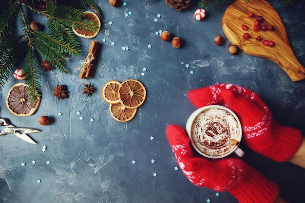 Photo christmas decoration with hands in warm mittens holding cup of cocoa or hot chocolate