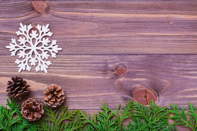 Christmas decoration with thuja branches, snowflake and  pine cones  on wooden table.