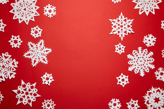 Christmas decoration with white snowflakes on red background flat lay