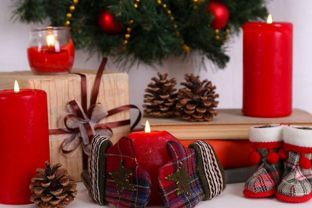 Christmas decoration with wreath, candles and present boxes on shelf on white surface wall surface