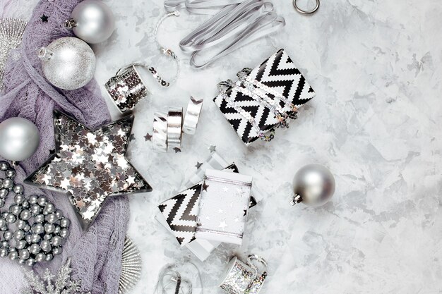 Photo christmas decorations, bows, stars in silver colour on grey background. holiday and celebration. flat lay, top view