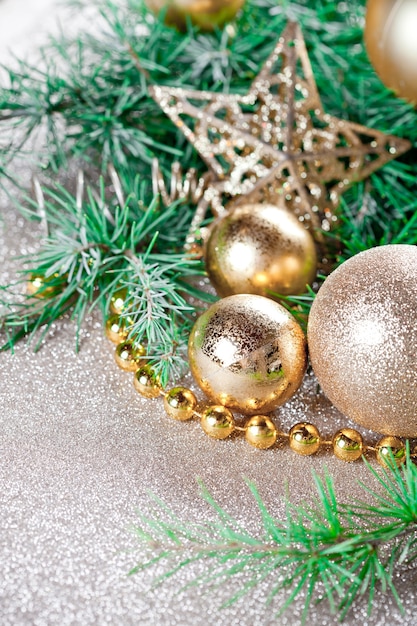 Christmas decorations and evergreen fir tree branch closeup on gold glitter.