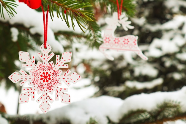 Christmas decorations snowflake and deer on a snow-covered spruce branch