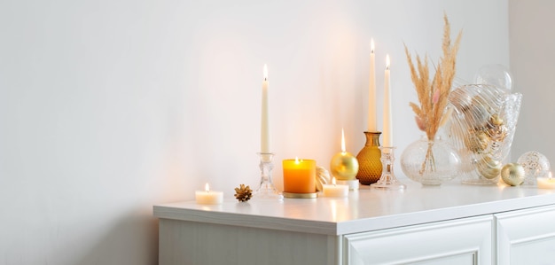 Christmas decorations with burning candles in white room