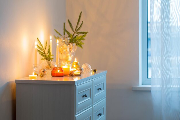 Christmas decorations with burning candles in white room