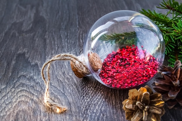 Christmas decorations with transparent glass ball spruce branch and cone on table