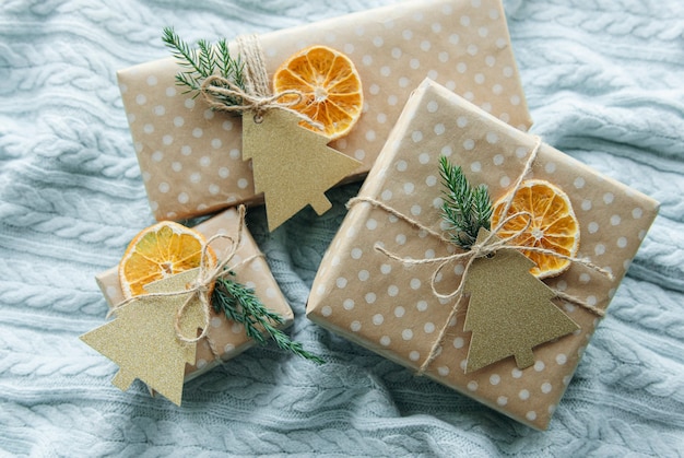 Christmas  decorative homemade gift boxes wrapped in brown kraft paper on a blue knitted textile background