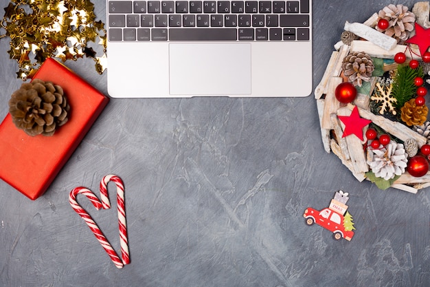 Christmas desktop with laptop, wreath, gift box and candy cane