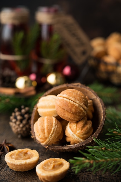 Christmas dessert cookies nuts with boiled condensed milk on a dark wall with garlands and Christmas decorations