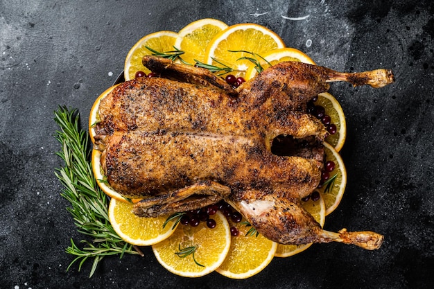 Christmas dinner baked duck with rosemary and oranges crispy whole roast duck Black background Top view