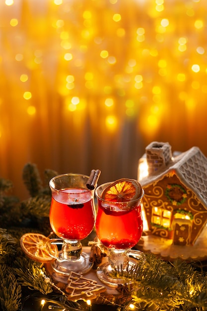 Christmas drink with spicy and berries with gingerbread house and spruce branches