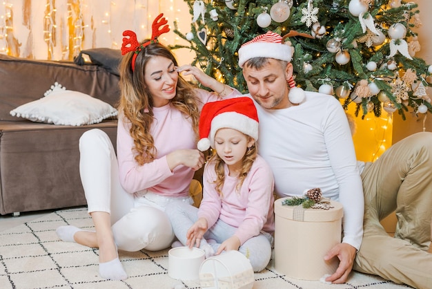 Christmas family Happy portrait dad mom and daughter in santa hats sitting