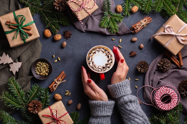 Christmas female hands with gift boxes and cup of coffee