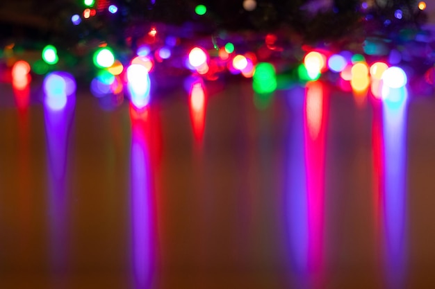 Christmas festive background with defocused garland lights reflected on shiny table surface