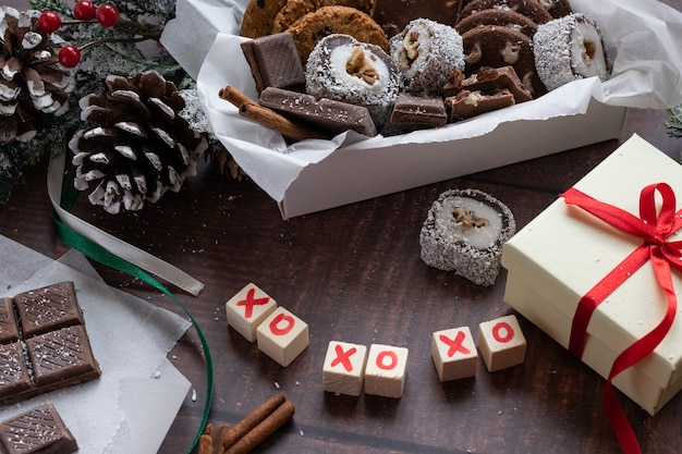 Christmas festive gift box and sweets with seasons decorations on wooden background