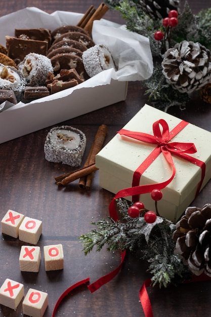 Christmas festive gift box and sweets with seasons decorations on wooden background