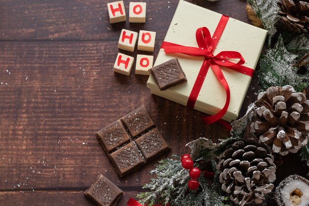 Christmas festive gift box and sweets with seasons decorations on wooden background