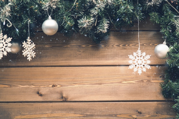 Christmas fir tree branches with decorations on a wooden board with snow.