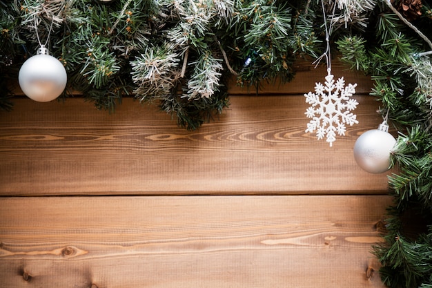 Christmas fir tree branches with decorations on a wooden board.