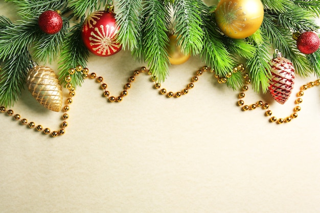 Christmas fir tree branches with toys and beads on paper surface