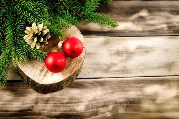 Christmas fir tree on natural wood with pine cone and red balls.