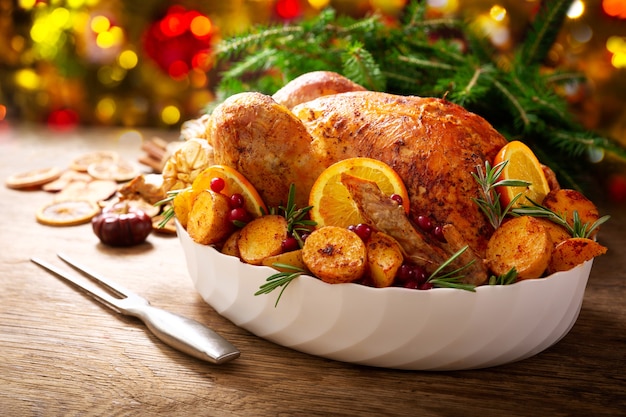 Christmas food. Baked turkey garnished with potato, oranges and  cranberries on a wooden table