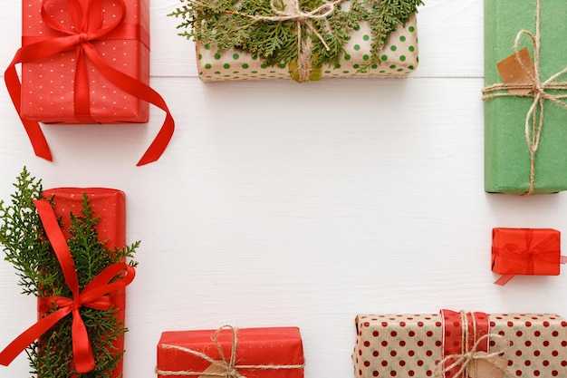 Christmas frame composition made of red, green, brown crafted Christmas gifts on white wooden table background. Christmas, Xmas, winter, new year concept. Flat lay, frame, top view, copy space.