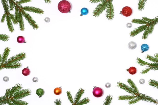 Christmas frame of fir branches and colored baubles on white background