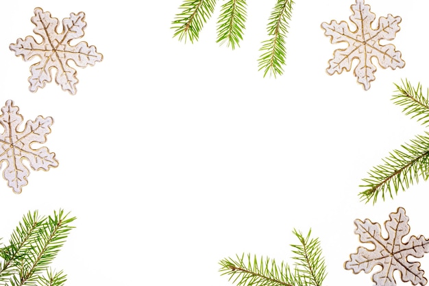 Christmas frame made of decorative snowflakes and green fir twigs on white backdrop Copy space