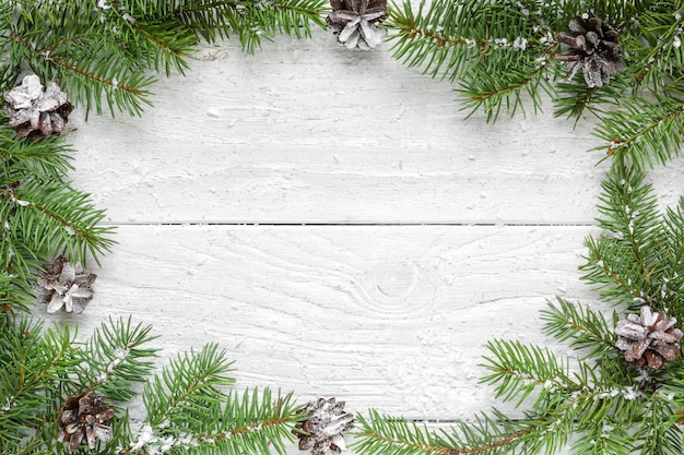 Christmas frame made of fir branches and pine cones on white wooden table. Christmas or happy new year background. Flat lay. top view with copy space