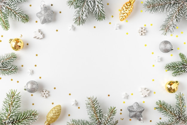 Christmas frame made of snow fir tree with golden and silver decorations on white background. Flat lay