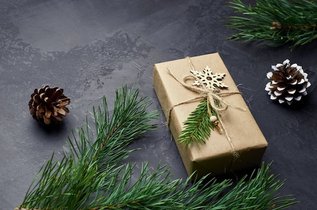 Christmas gift box with pine branches and cones on dark