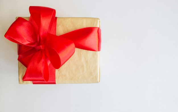 Christmas gift box with red ribbon and spruce branch on the white over pine cones