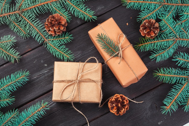 Christmas gift boxes and fir tree branch on wooden table.