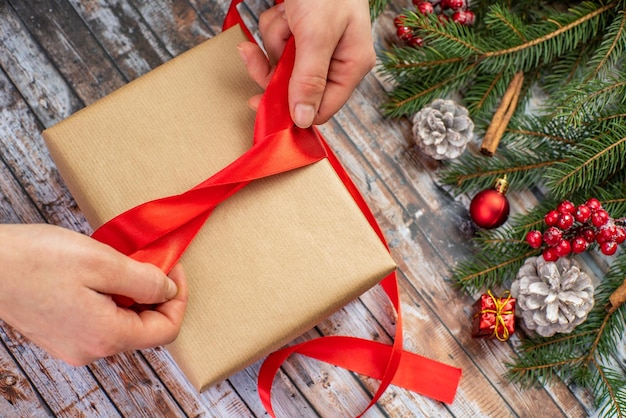 Christmas gift girl wraps a gift with a red ribbon closeup