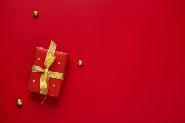 Christmas gift and gold decor on red background with copy space.