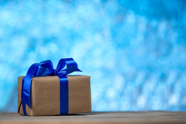 Christmas gift or New year with a blue ribbon on a rustic wood table on a night blue bokeh