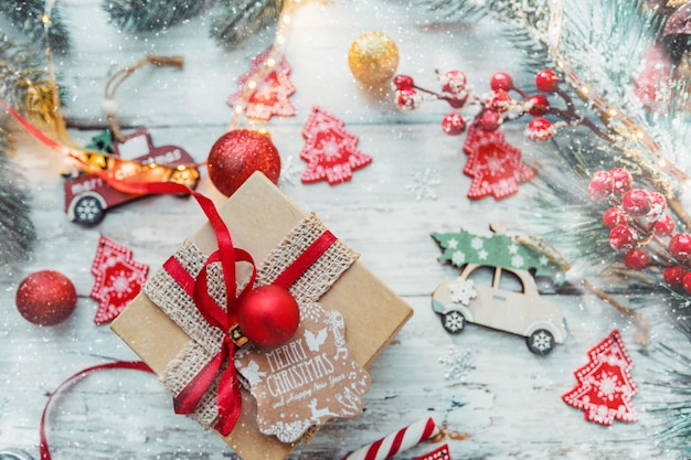 Christmas gift with a red ribbon toys on a wooden background with snowflakes