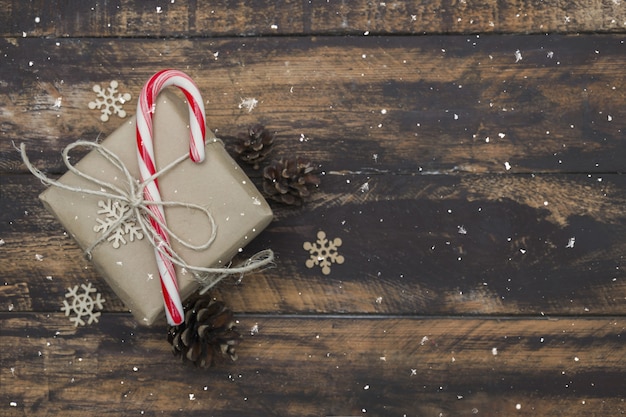 .Christmas gift wrapped in craft paper with candy cane on brown wooden table.