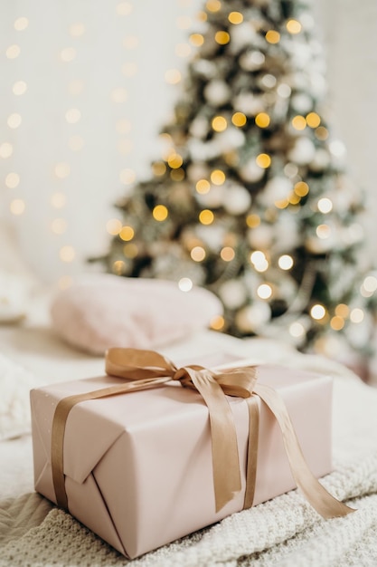 Christmas gifts in pink packaging with a bow on the background of the Christmas tree