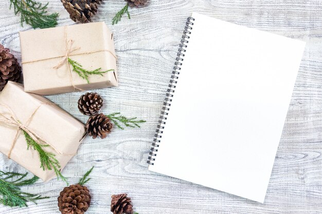 Christmas gifts on a white wooden background with fir tree and pine cones 