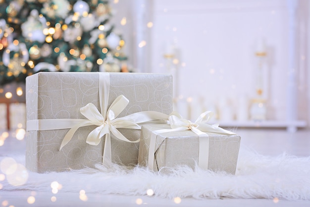 Christmas gifts with white ribbon under christmas tree.