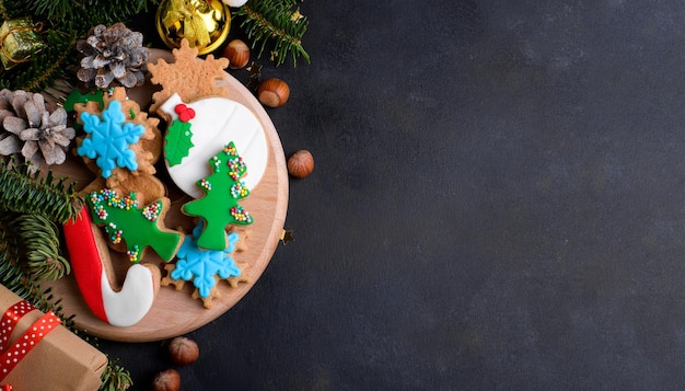 Christmas gingerbread cookies with sugar paste and fresh fir tree Christmas decoration on dark background copy space