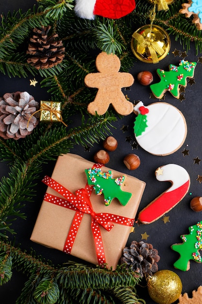 Christmas gingerbread cookies with sugar paste and natural fir tree and Christmas decoration on dark background