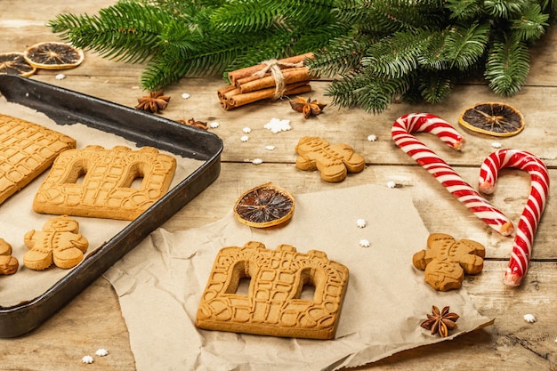 Christmas Gingerbread House and Gingerbread Men. Traditional festive New Year design, cooking process. Old wooden background, rustic style, close up