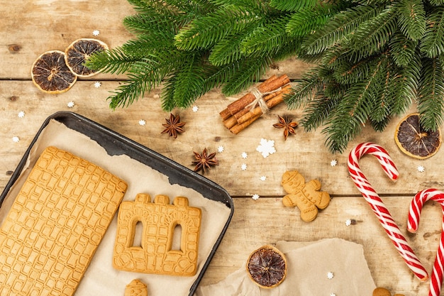 Christmas Gingerbread House and Gingerbread Men. Traditional festive New Year design, cooking process. Old wooden background, rustic style, top view