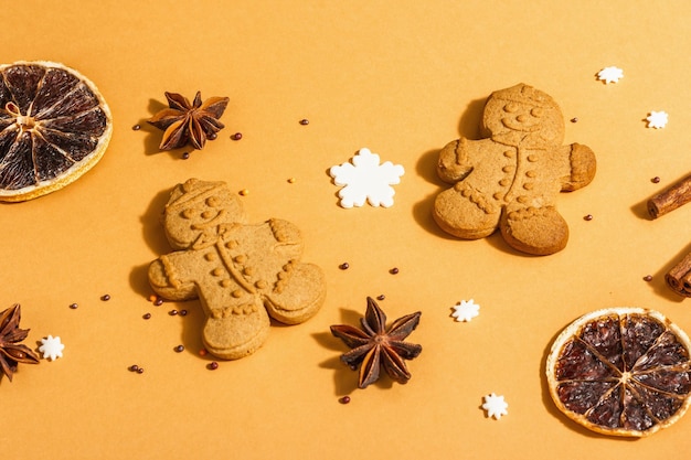 Christmas Gingerbread Men with fragrant spices. Traditional festive New Year decor. Trendy hard light, dark shadow, beige background, flat lay, close up