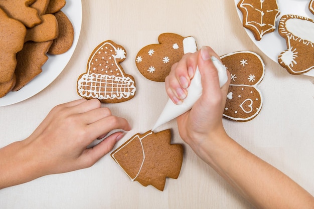 Christmas gingerbread painting. The child is icing the drawing on the cookie.