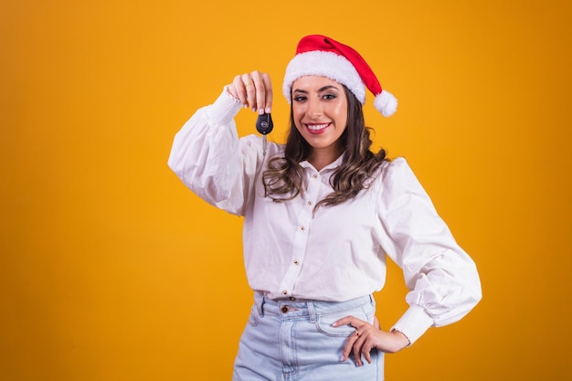 Christmas girl in santa hat holding auto keys. Isolated.